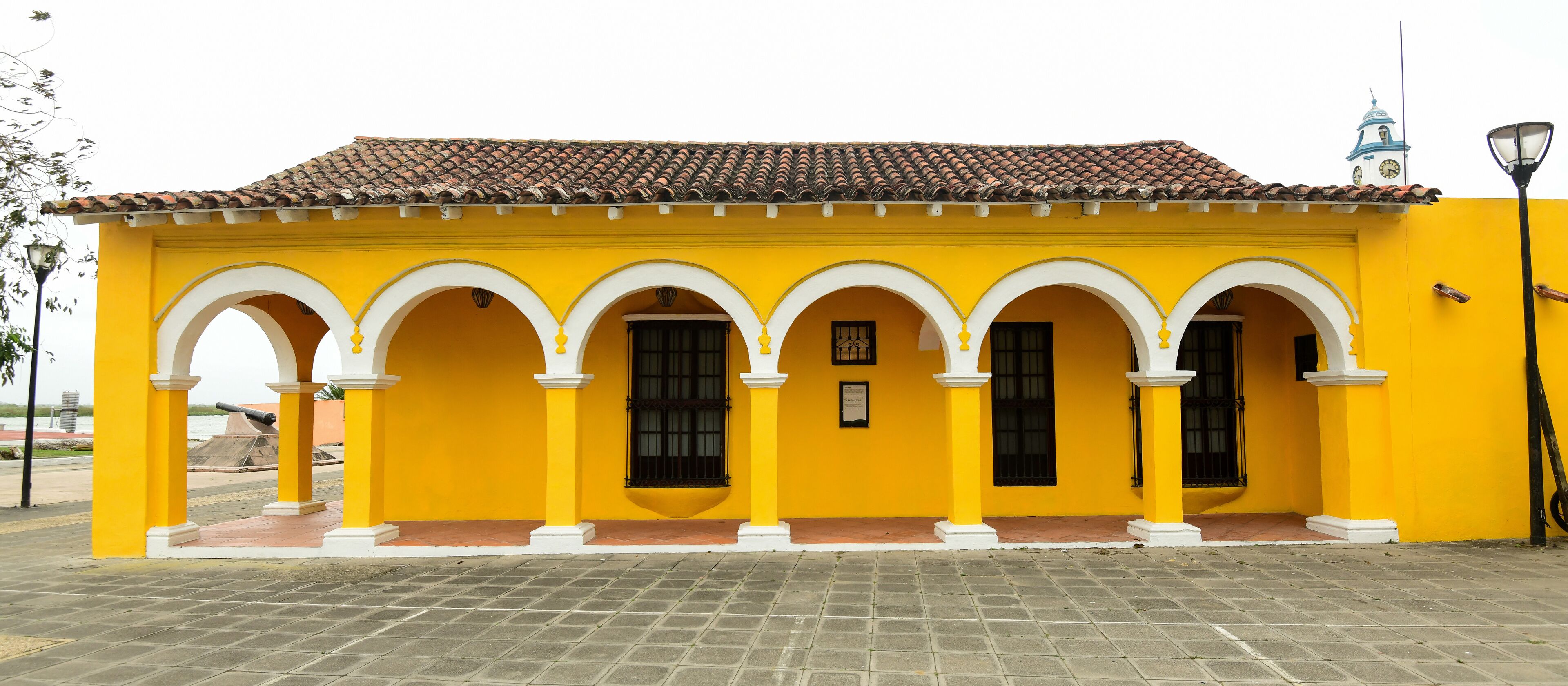A yellow building with a tiled roof and white arches.