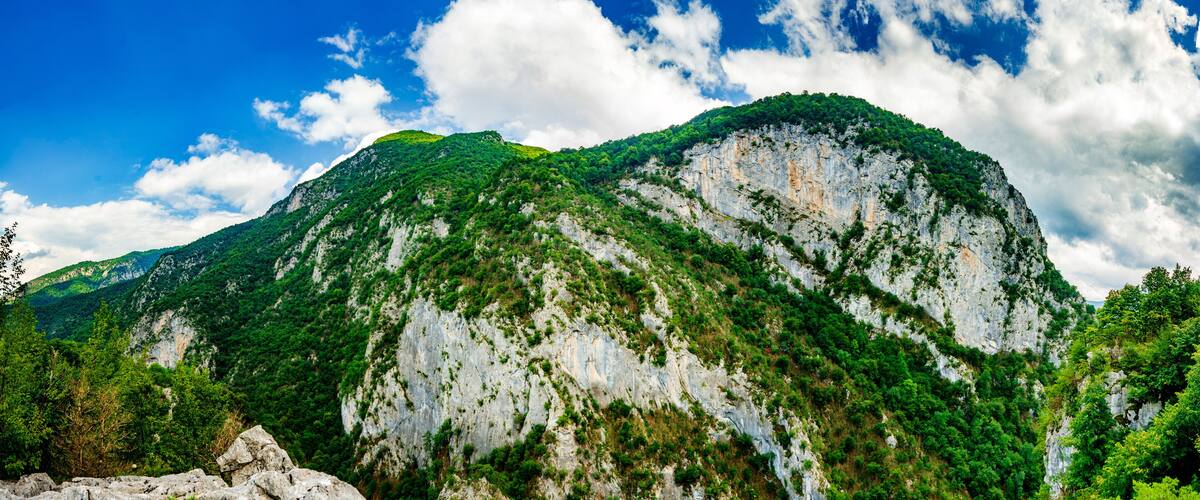 A mountain with a prominent rocky face and lush green vegetation.