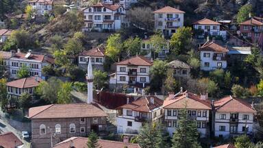 Um bairro residencial em encosta, com casas em terraços, uma torre de igreja imponente e vegetação exuberante.