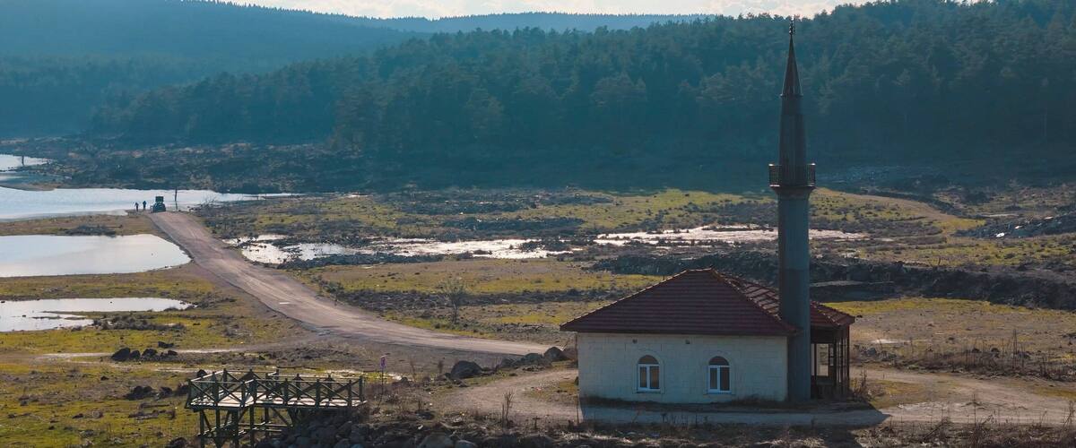 A rural landscape with a church, a watchtower, and a river.