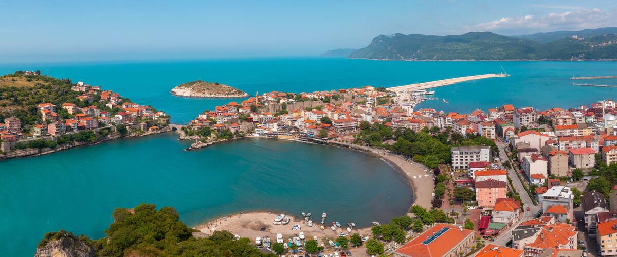 A coastal town with a prominent hill, a bay, and a pier extending into the sea.