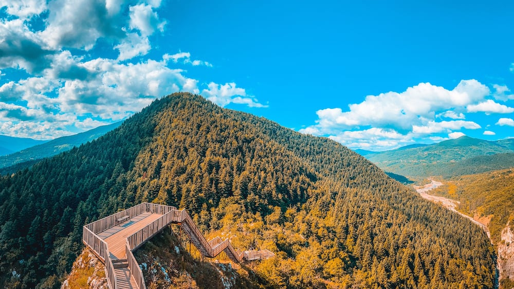 Une montagne boisée surmontée d’une plateforme d’observation en bois.