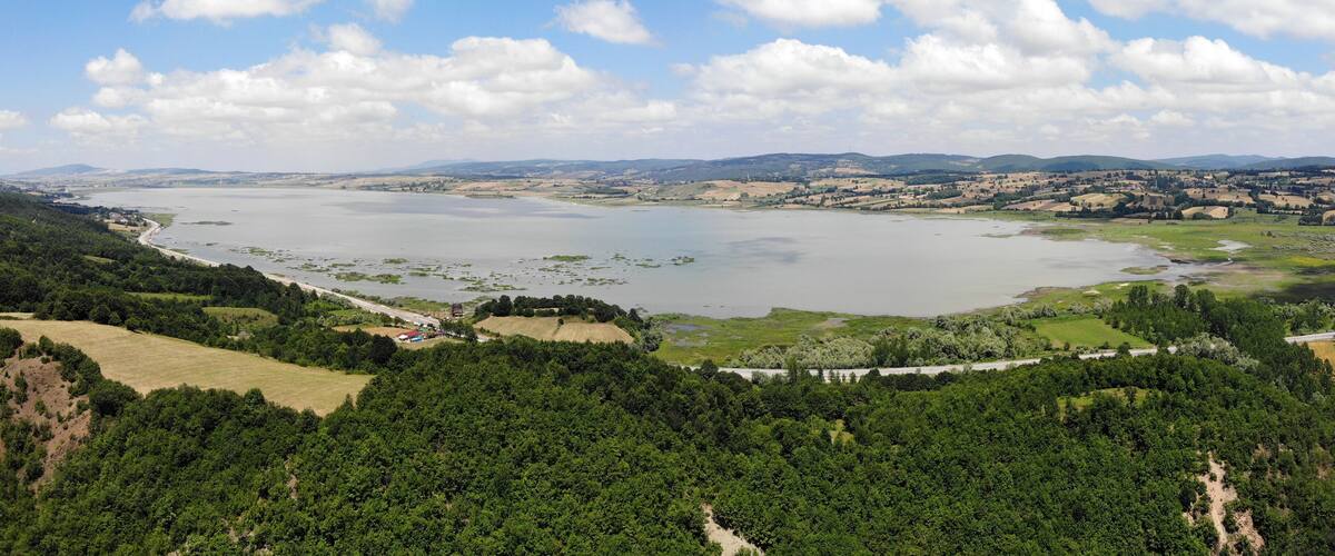 A river winding through a valley with hills in the background and a clear sky.