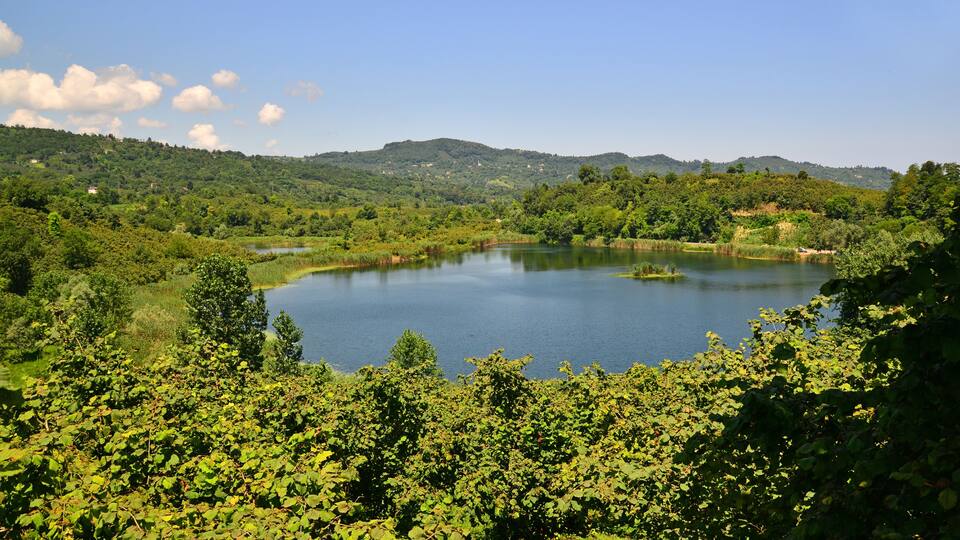 A lake surrounded by lush greenery and hills.