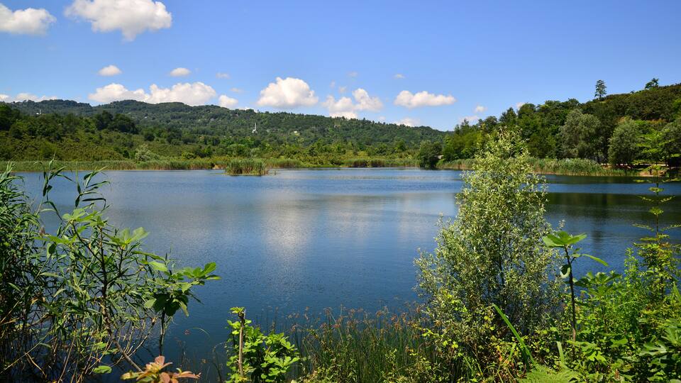 A calm lake surrounded by lush greenery and hills.