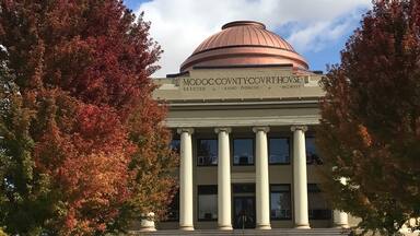A large building with a dome and columns, surrounded by trees with autumn leaves.