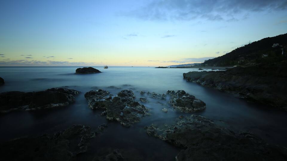A coastal landscape with rocky formations and calm waters.