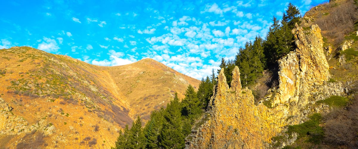 A mountainous landscape with rocky cliffs and dense forests.