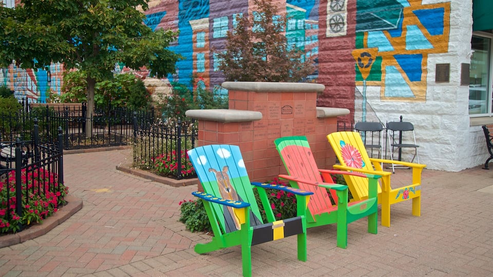 Colorful Adirondack chairs in front of a building with a mural.