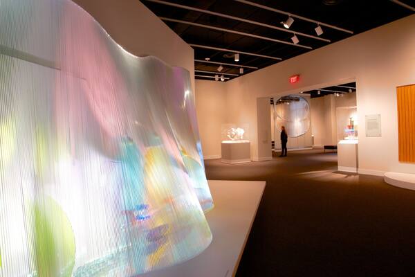 An art gallery with large, colorful installations and a wooden panel on the wall.