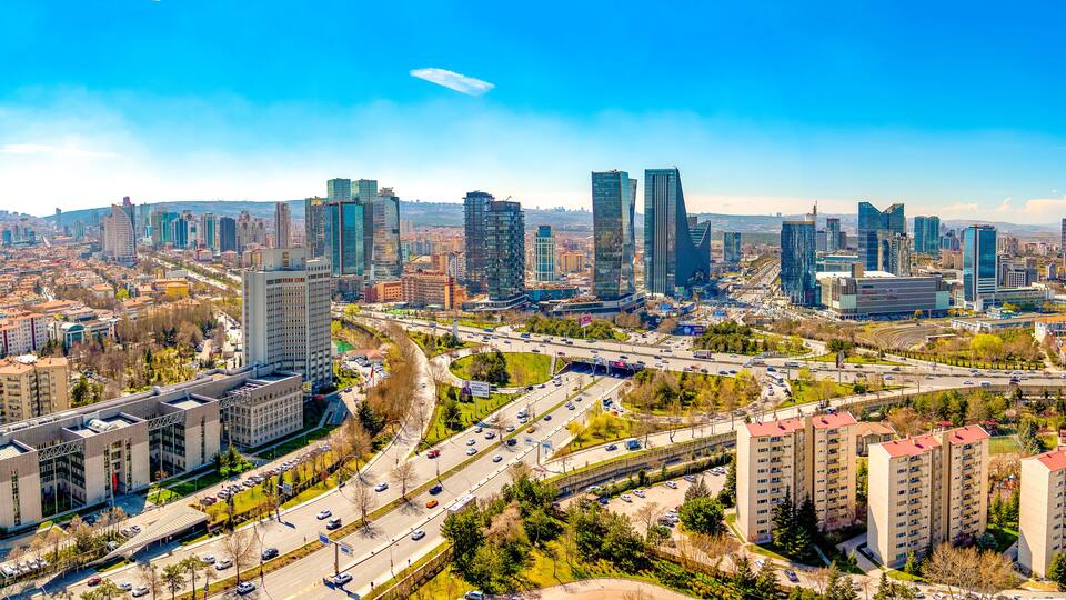 A cityscape with modern skyscrapers, a highway, and surrounding greenery.