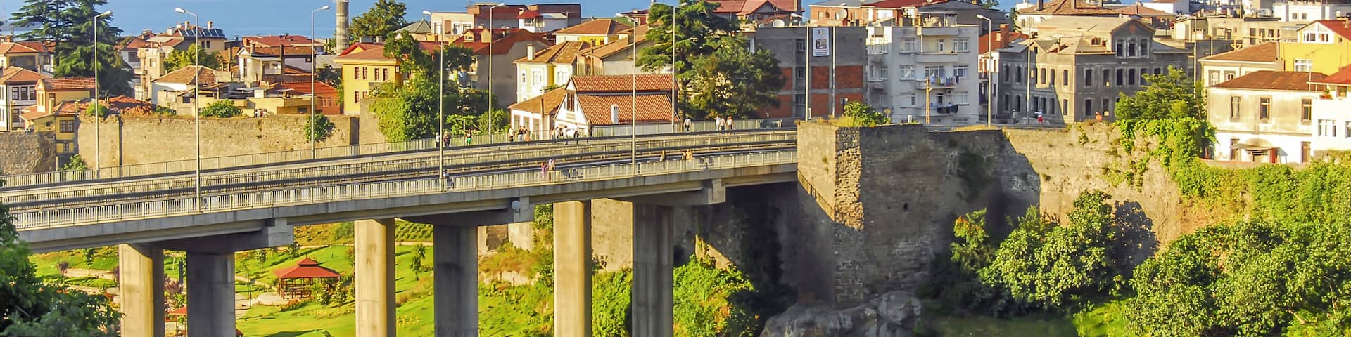 A bridge over a valley with a mosque and a castle in the background.