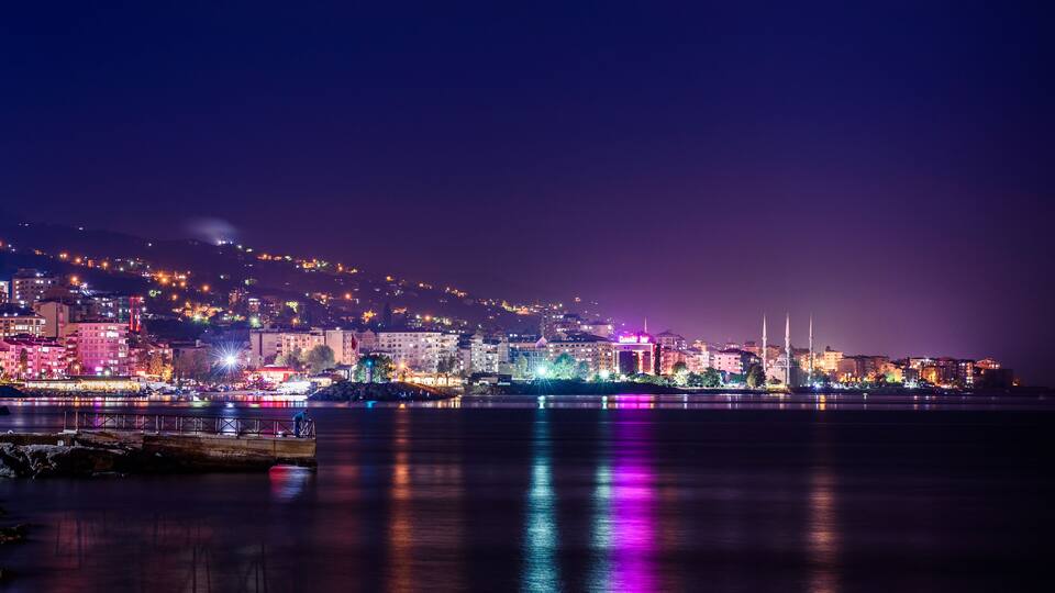 Une vue nocturne d’une ville, avec des bâtiments illuminés et une mosquée dotée de deux minarets.