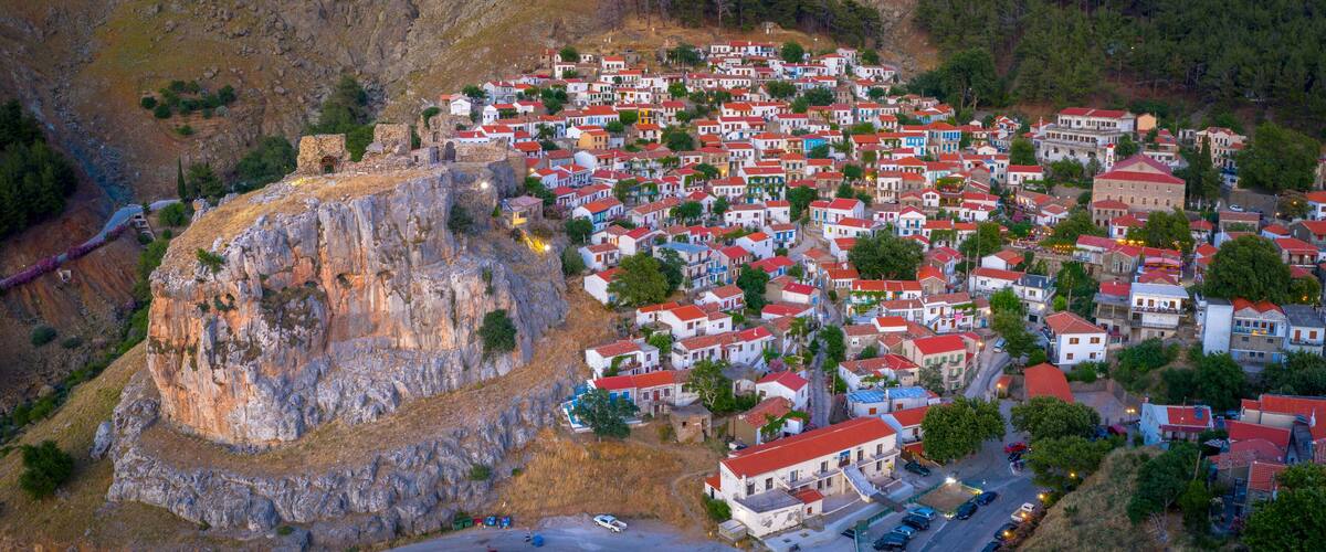 A coastal village with colorful houses, a prominent cliff, and a historic building.