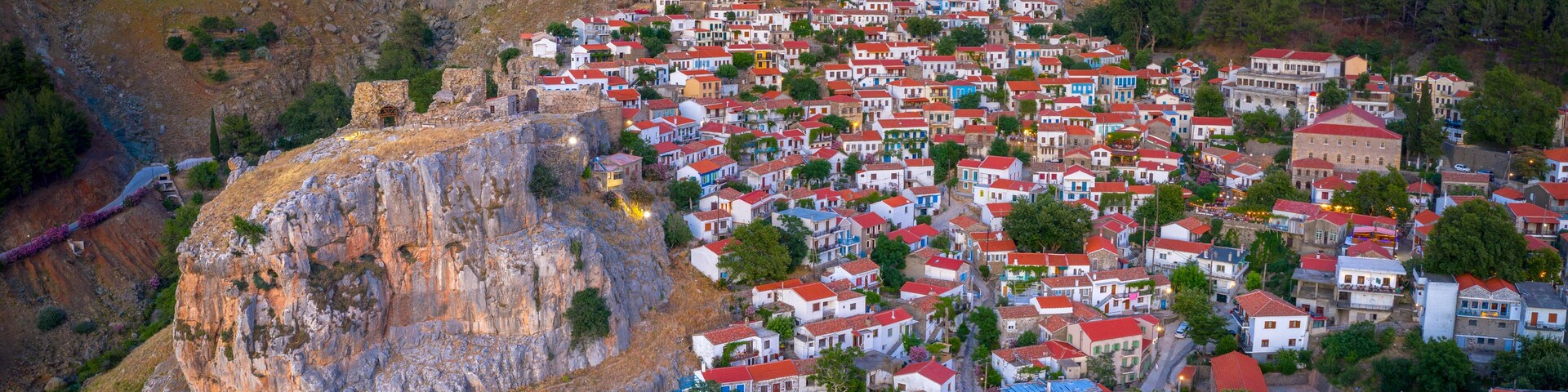 A coastal village with colorful houses, a prominent cliff, and a historic building.