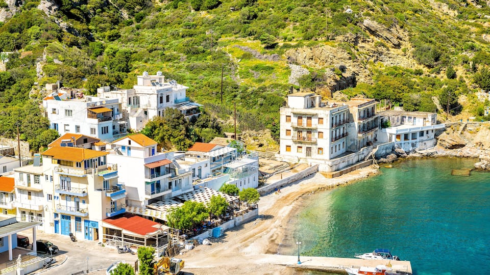 A coastal village with buildings, a beach, and a boat docked near the shore.