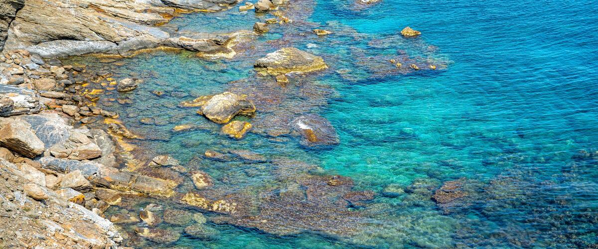 A rocky shoreline with clear blue water.
