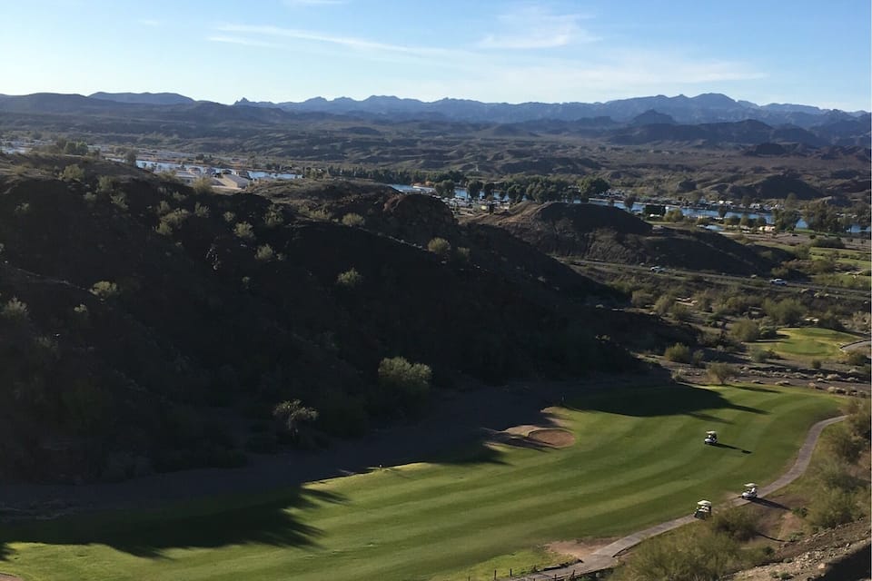 A golf course with a river and mountains in the background.