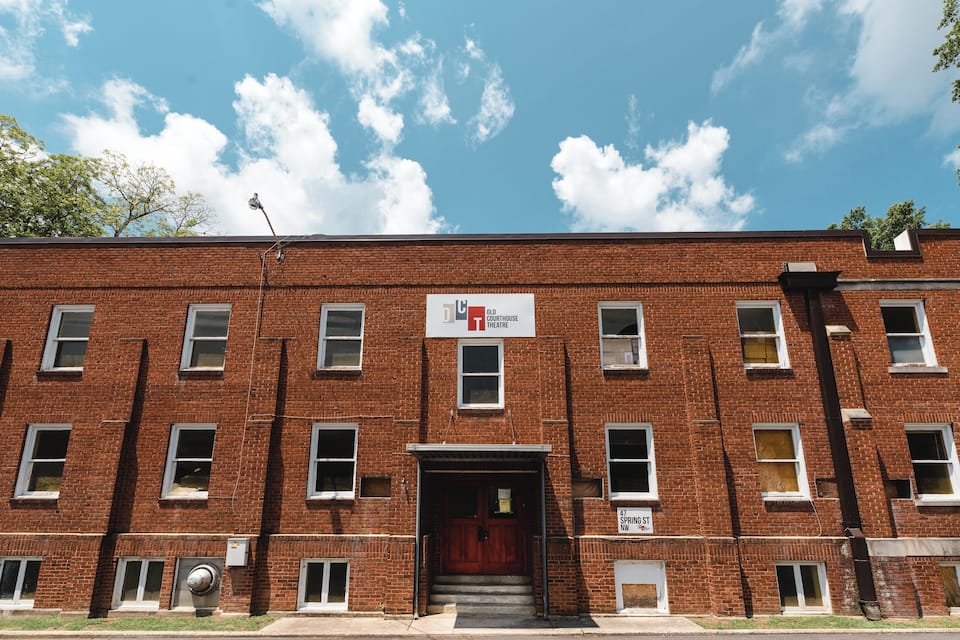 A red brick building with a sign for the Old Courthouse Theatre.