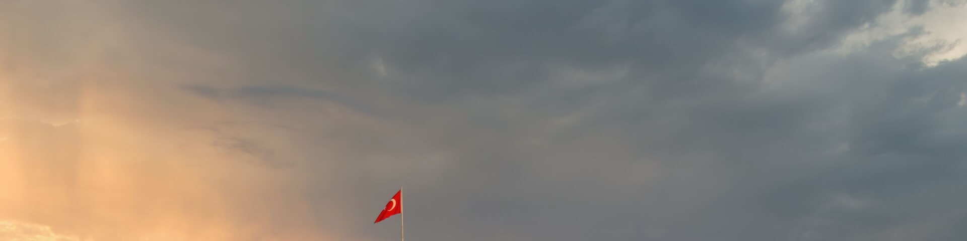 Una fortaleza costera con una bandera, rodeada de agua y nubes espectaculares.
