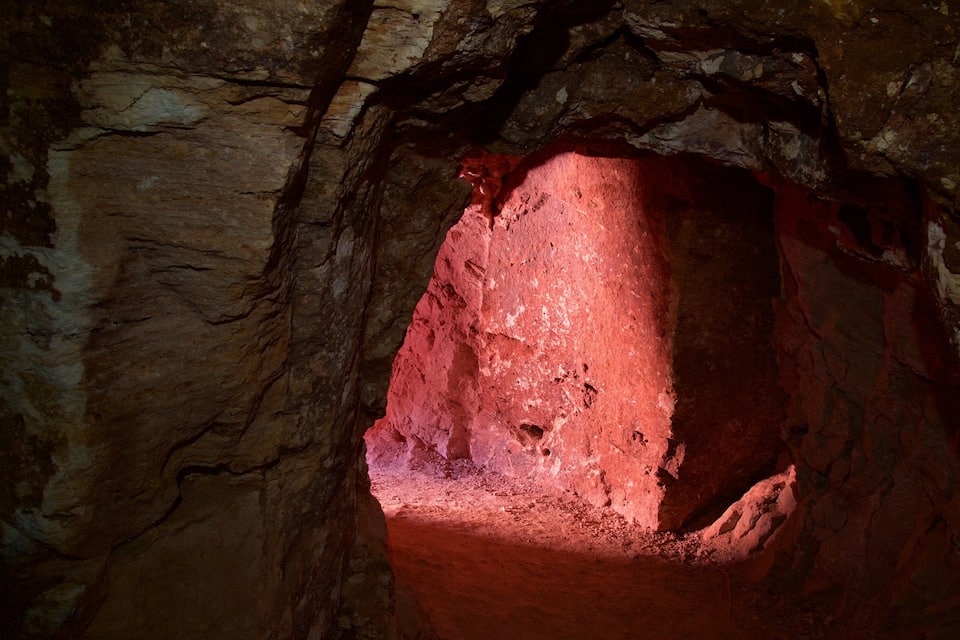 A cave with a red-lit opening and rough rock walls.