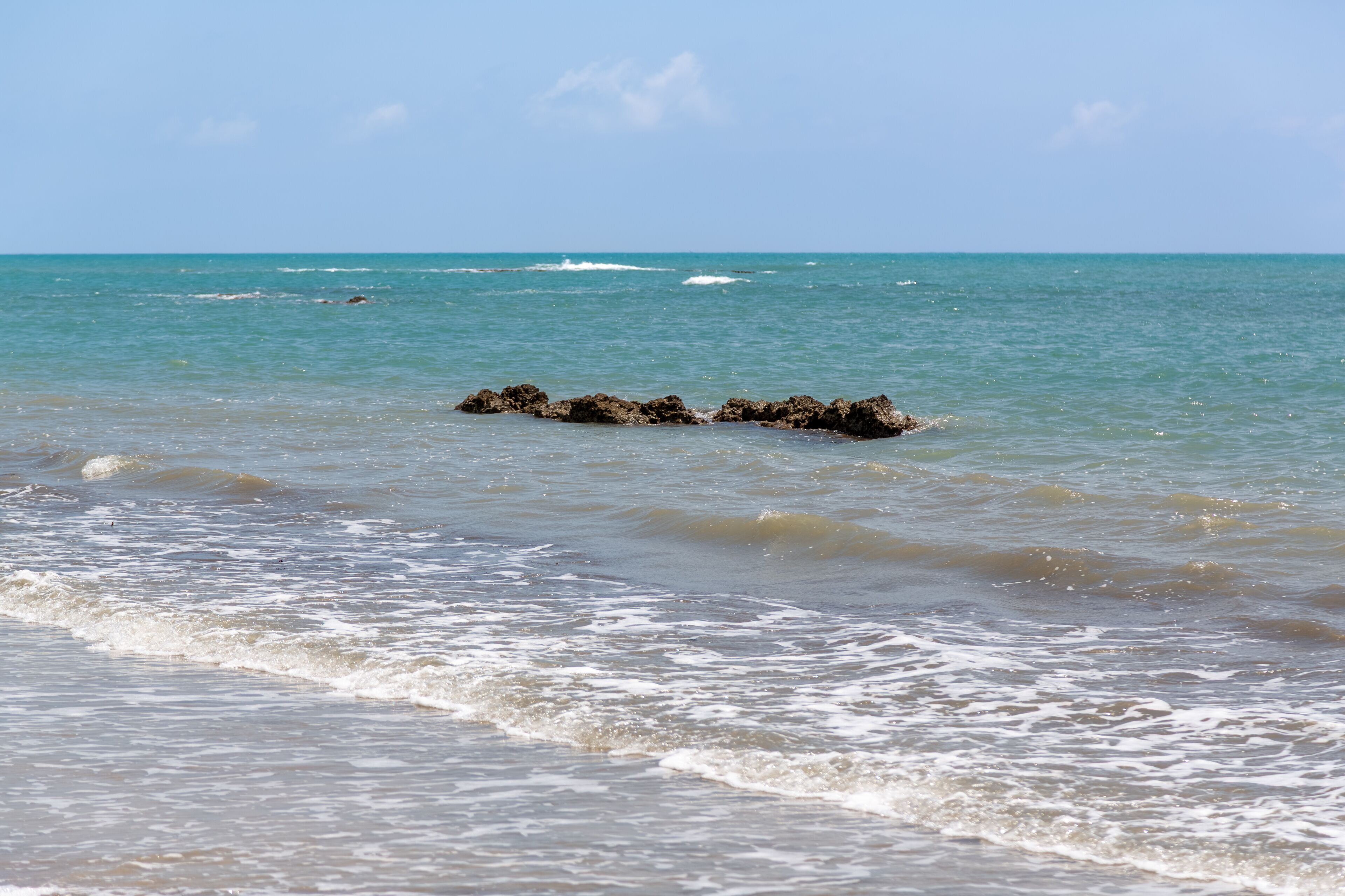 Sand, rocks, and calm waves. Turquoise sea and sparkling waters. Karataş, Adana, Türkiye.