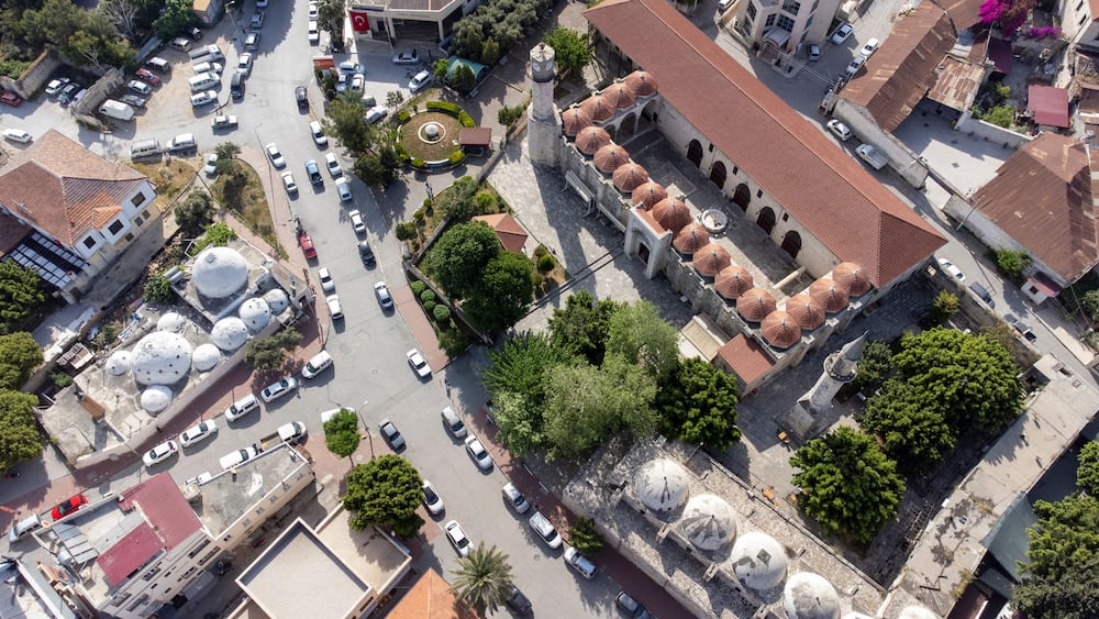 An aerial view of a city with a prominent mosque featuring multiple domes and a minaret.