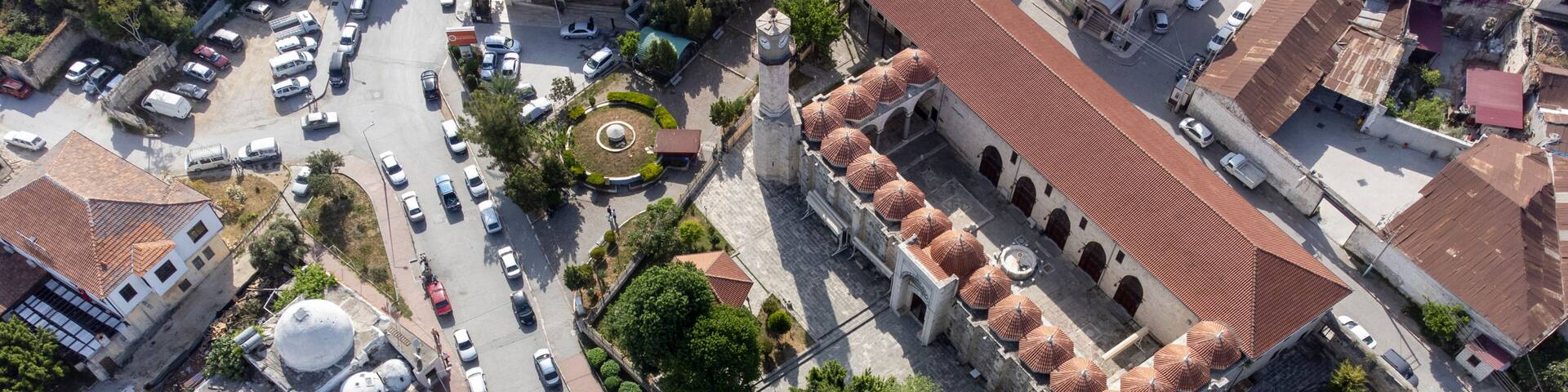 An aerial view of a city with a prominent mosque featuring multiple domes and a minaret.