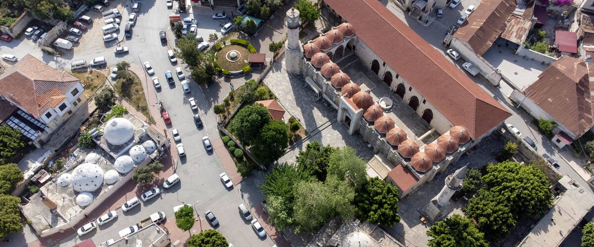 An aerial view of a city with a prominent mosque featuring multiple domes and a minaret.