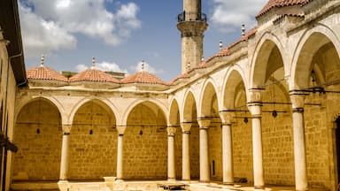A historic courtyard with arches, a tower, and a mosque.