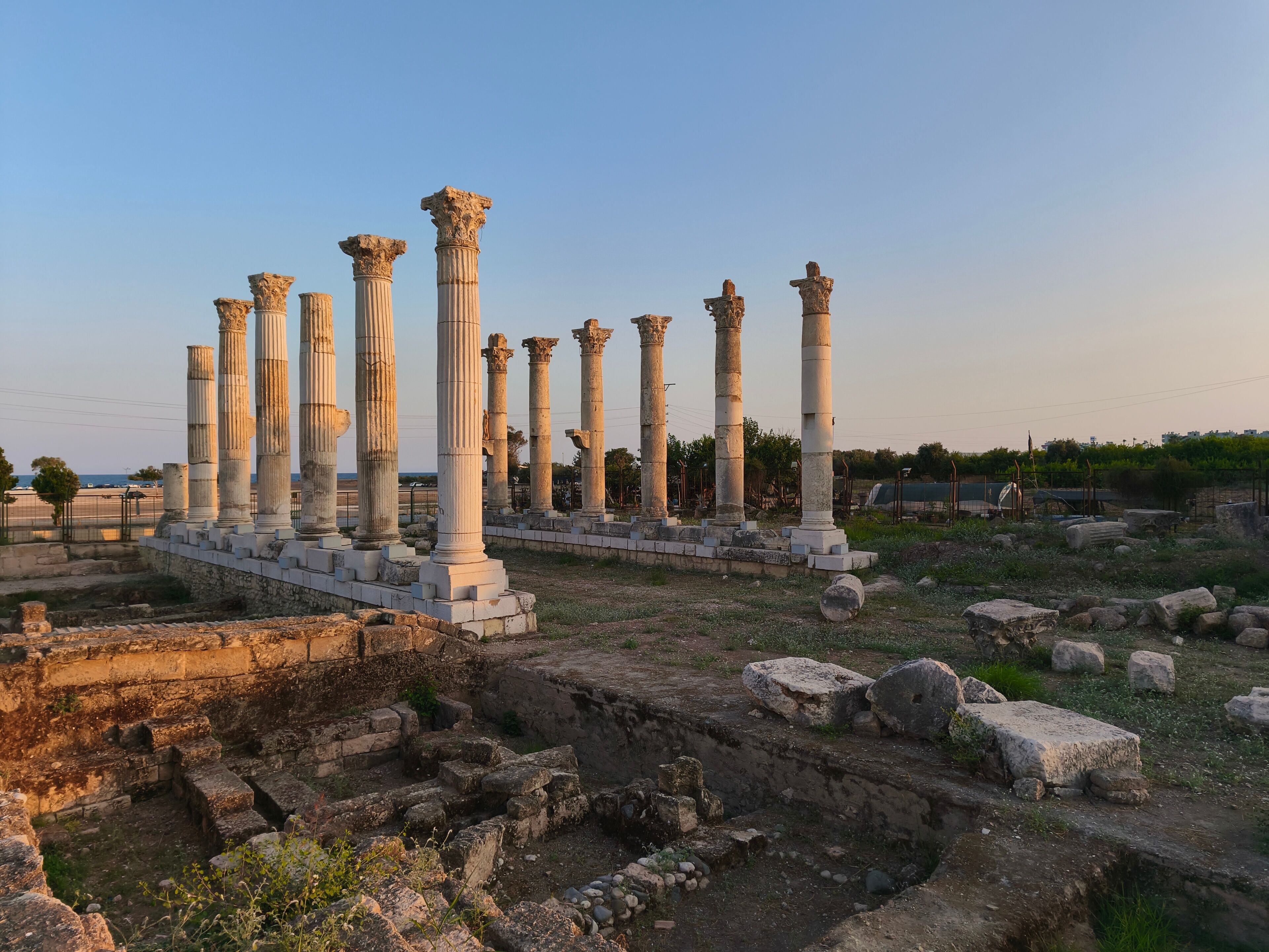 Columnas blancas antiguas en ruinas, rodeadas de bloques de piedra y un cielo despejado.