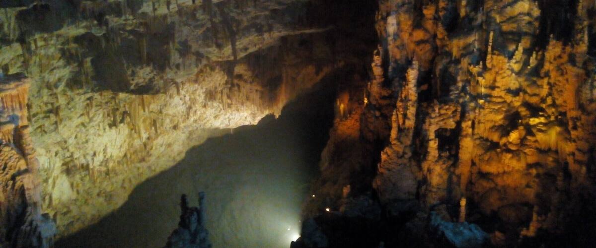 A cave interior with stalactites and a pool of water.