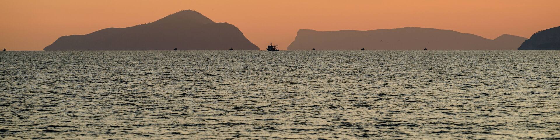 Tisan Dana Island in sunset and some boats seem barely far away, selective focus, Mersin Turkey