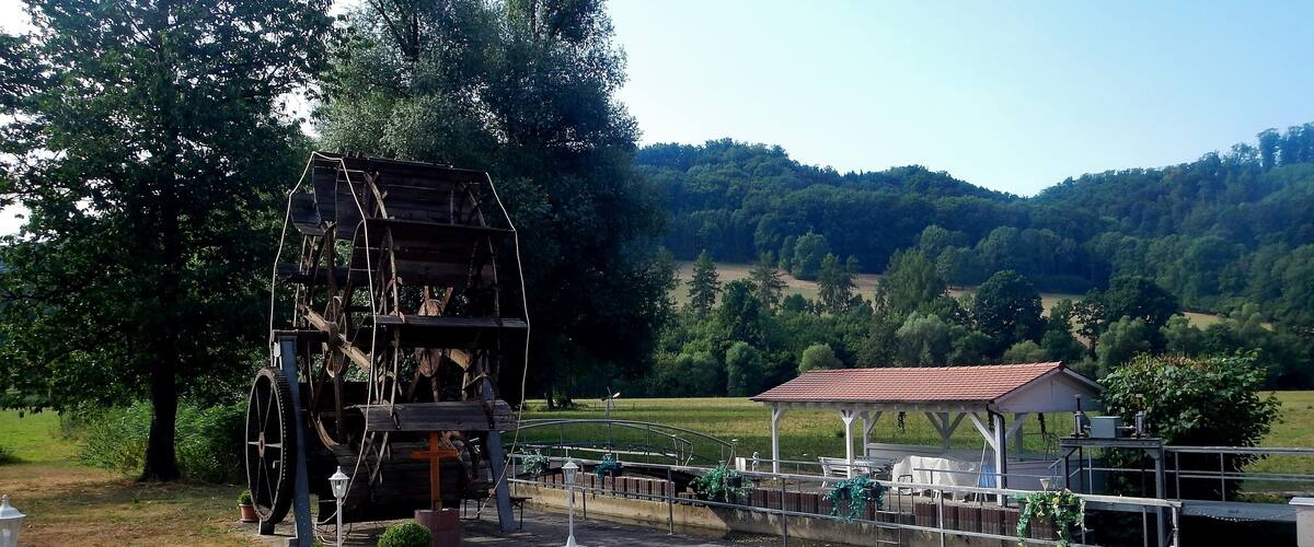 A historical watermill, a gazebo, and a scenic hillside.