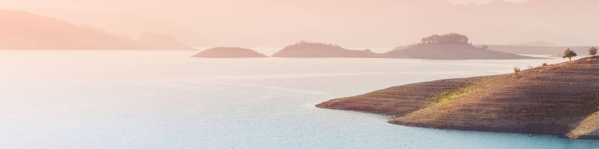 Panoramic inspirational and tranquil landscape in the rays of the sun in the morning. Idyllic nature with silhouettes of the Taurus mountains. Karacaoren lake in the Isparta region of Turkey.
