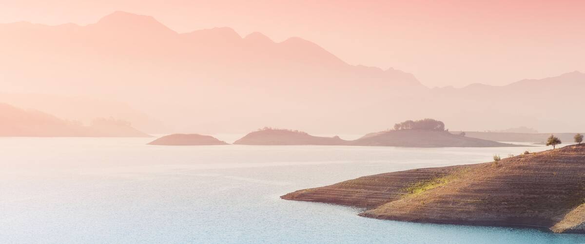 A calm lake with distant mountains and small islands.