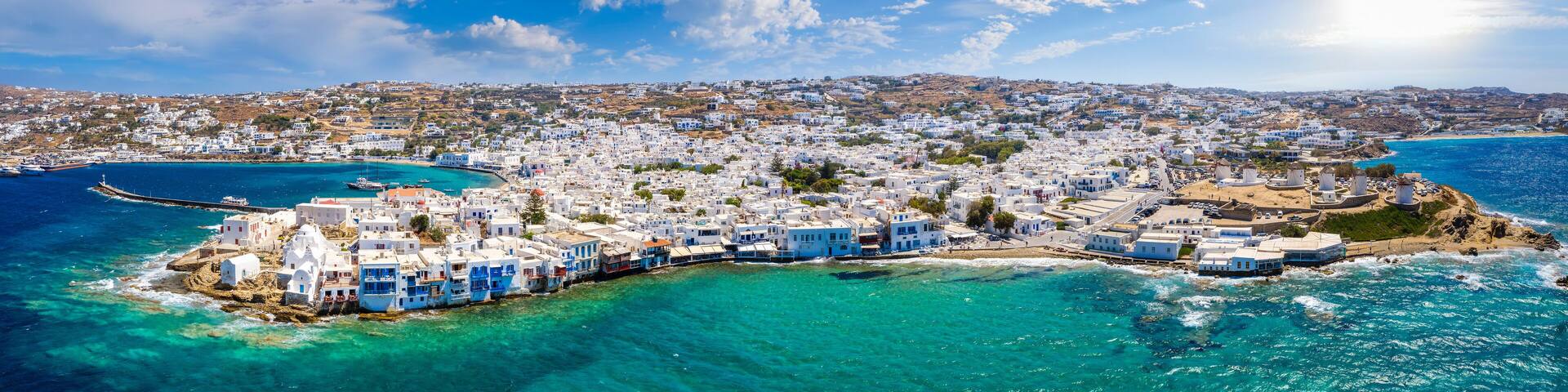 Wide aerial panorama of the town of Mykonos island, Greece, with the little venice district, the famous windmills and the old port