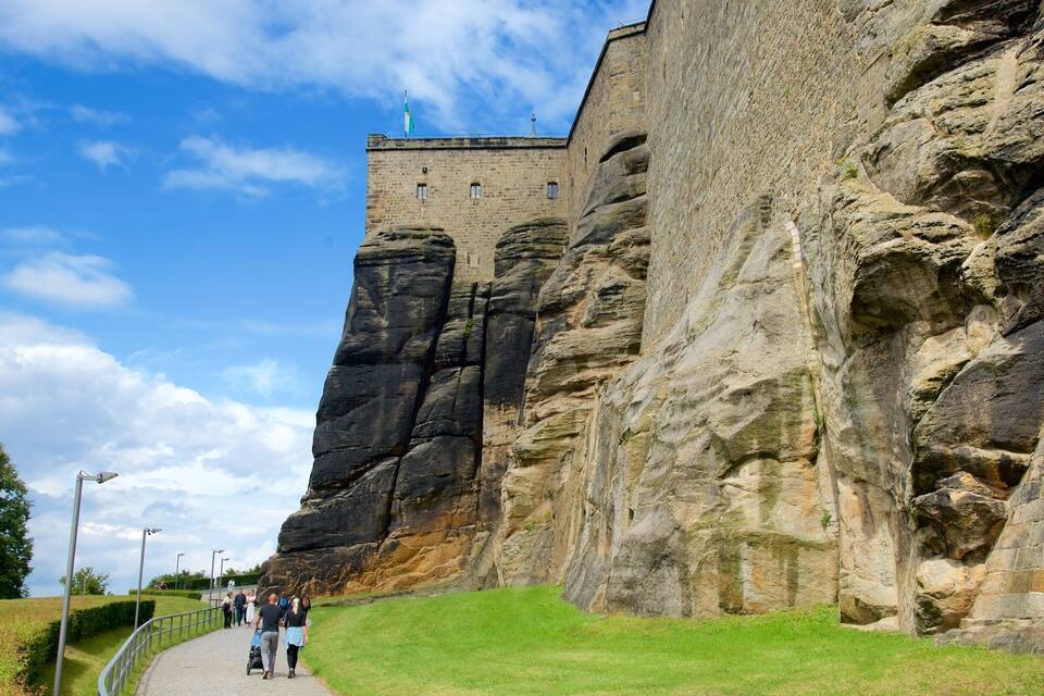 Eine historische Steinburg thront auf einem steilen Felsen, und ein Pfad führt hinauf zu ihr.