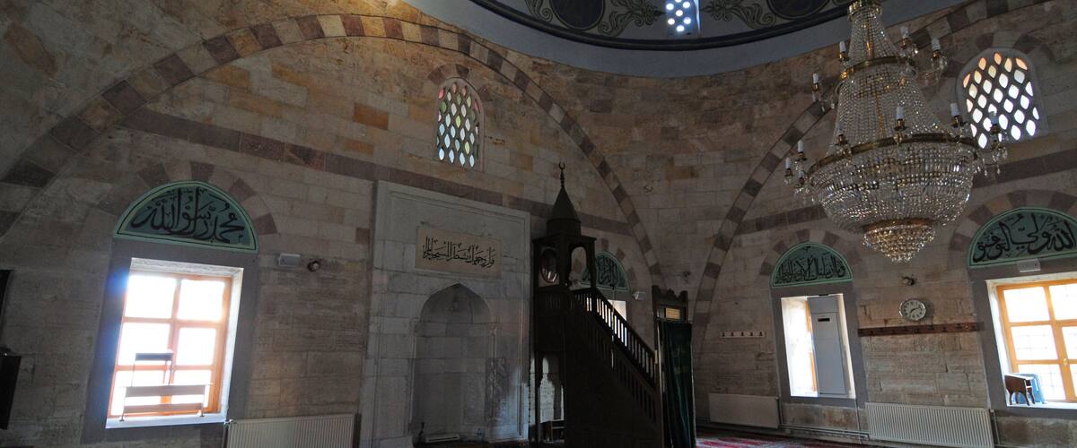 An interior with arched ceilings, a chandelier, and patterned carpets.