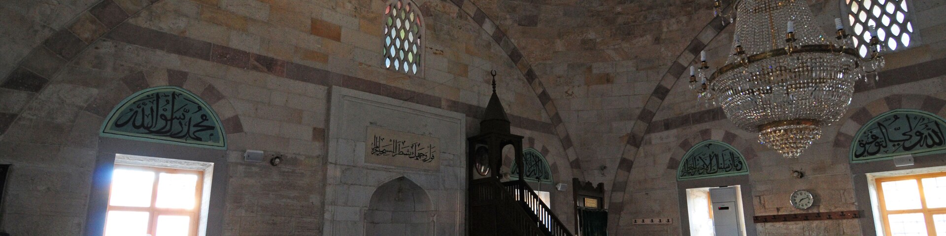 An interior with arched ceilings, a chandelier, and patterned carpets.