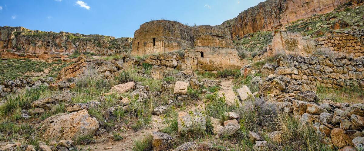 A rocky landscape with ancient ruins and a clear blue sky.