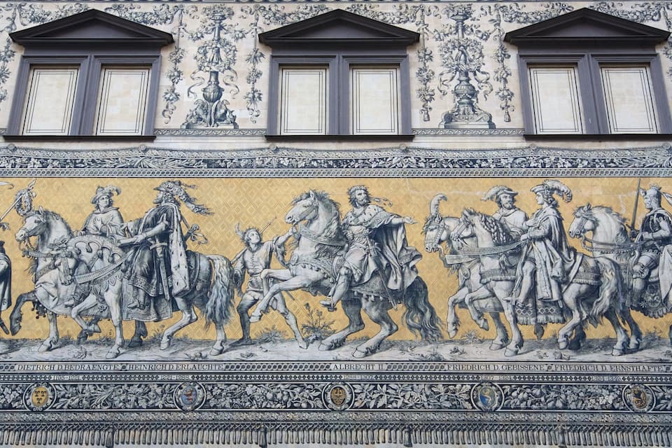 A detailed mural with three windows and a row of knights on horseback.