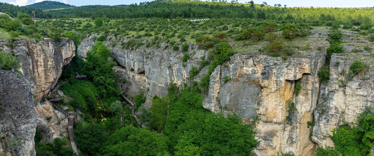 A rocky cliff with a wooden staircase leading up.