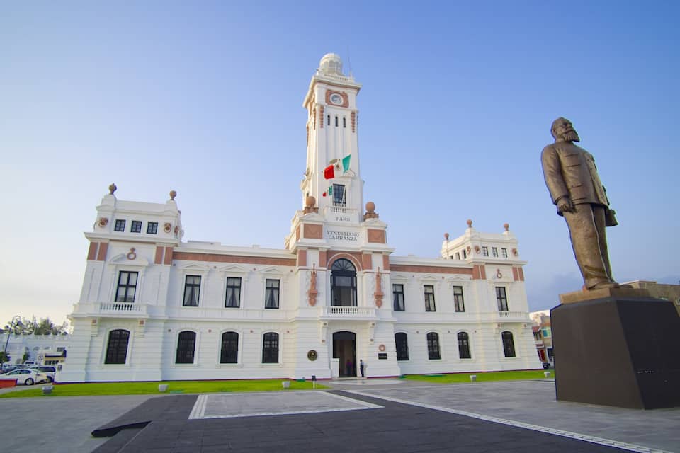 Un edifici històric amb una torre de l'ajuntament, una estàtua i una bandera.