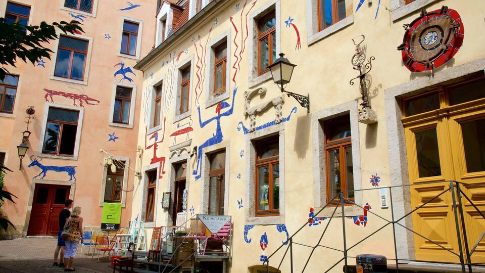 A colorful street with artistic murals, a yellow door, and a sign for 'Kunstladen'.