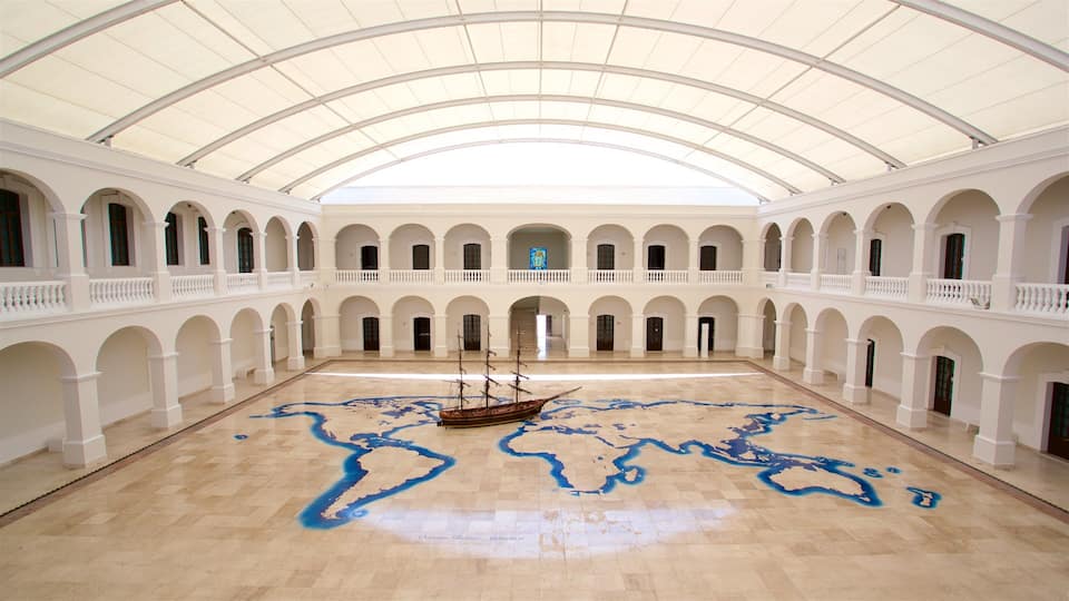 Un ampio cortile aperto con pavimento piastrellato decorato con un motivo a mappa, un modellino di nave e un tetto in vetro.