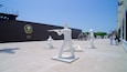 A naval museum with white statues of sailors and a large emblem on the wall.