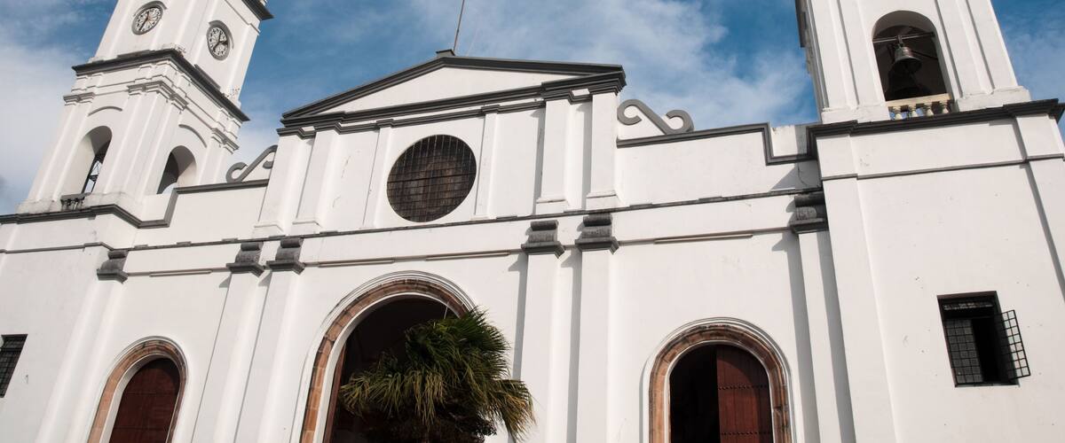 A white church with two bell towers and a cross on top.