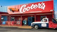 Een rode gevel met een oldtimer en de naam 'Cooter's' op het bord.