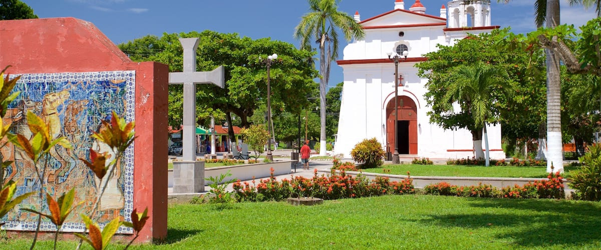 A church with a cross, surrounded by greenery and a tiled mosaic.